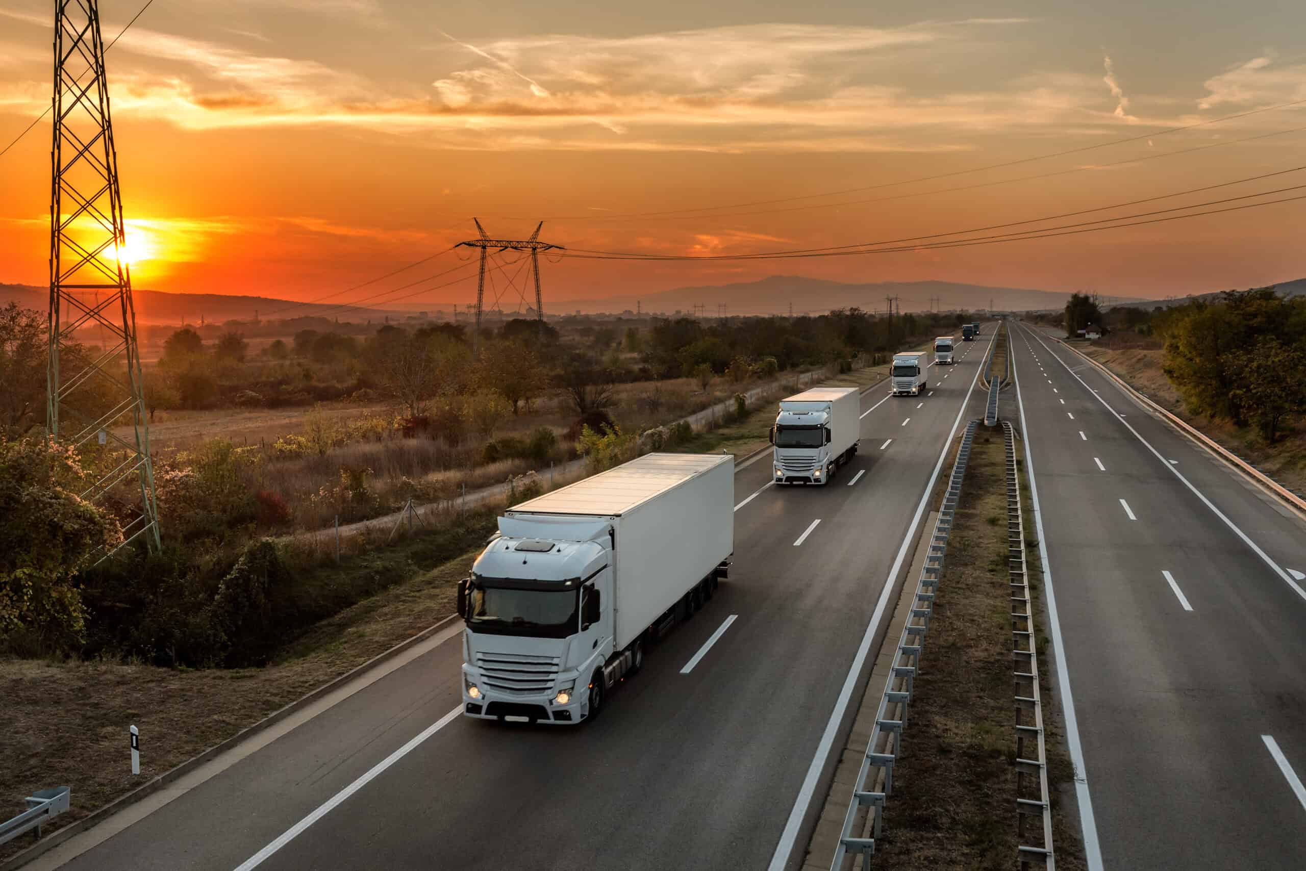 Convoy of blue lorry trucks on a country highway under amazing o